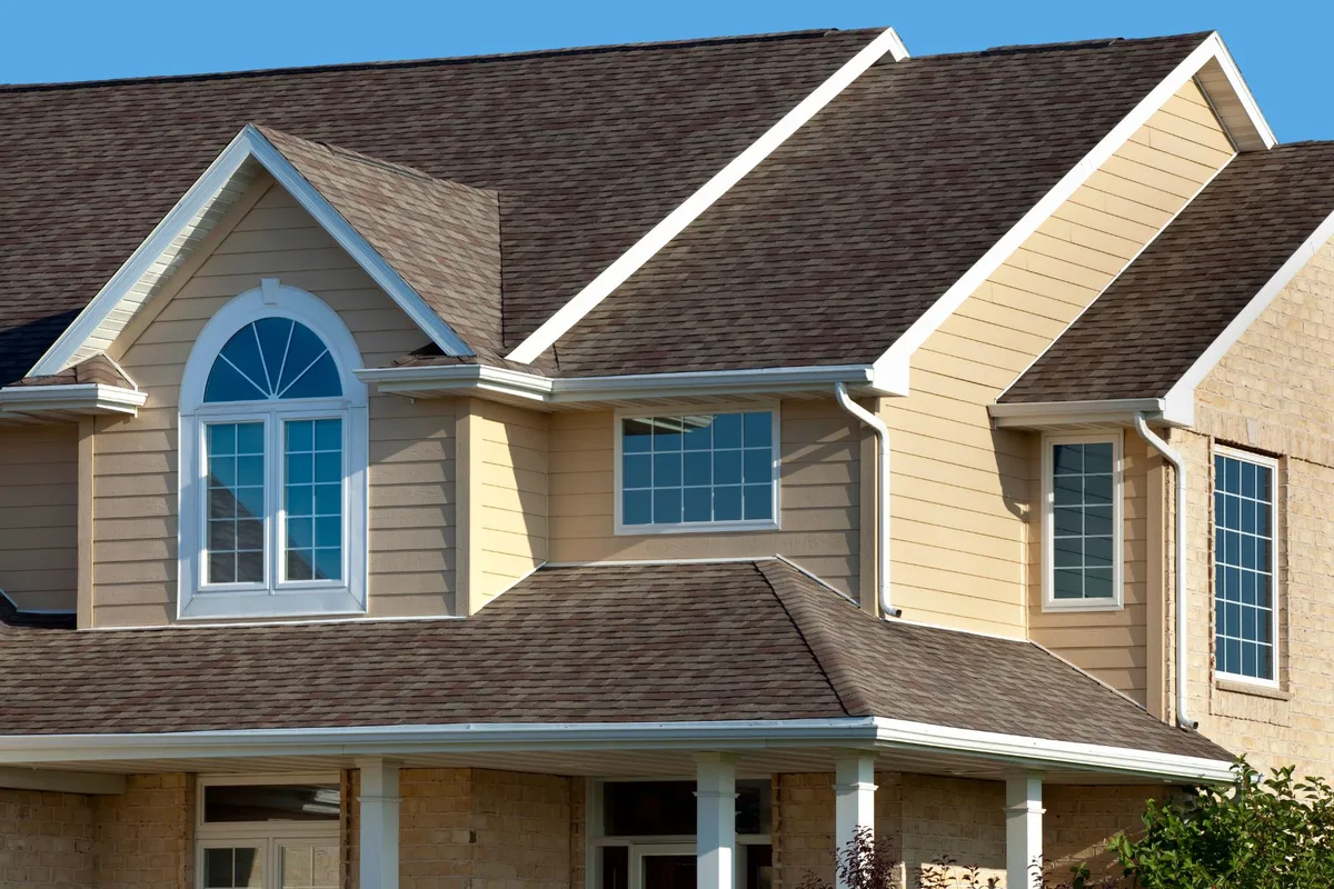 Close-up of cream lap siding and a green gable with brown shutters