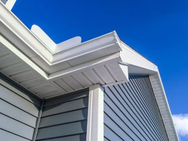 Close-up of gray lap siding with white soffit, vents and gutters