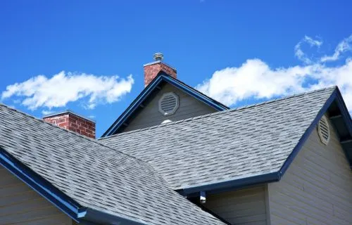 Completed residential shingle roof with chimneys and ridge vents