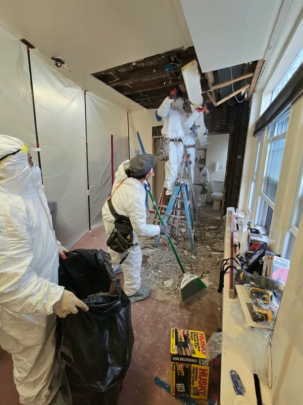 Crew in protective suits performing interior demolition and cleanup after damage