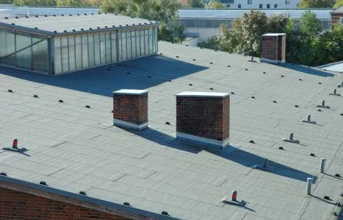 Flat commercial roof with brick chimneys, vents and skylights