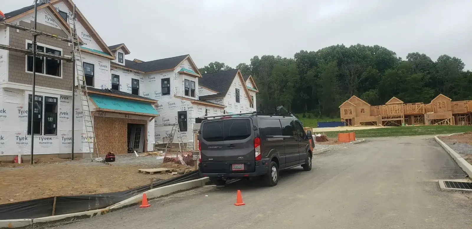 New home construction site with Tyvek house wrap, ladder, scaffold and work van