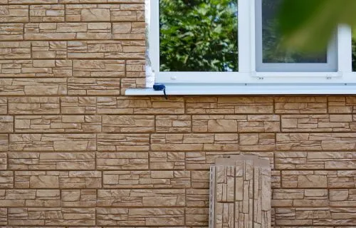 Insulated stone-look siding panels installed around a window