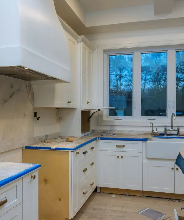 Kitchen renovation in progress with white cabinets and a farmhouse sink