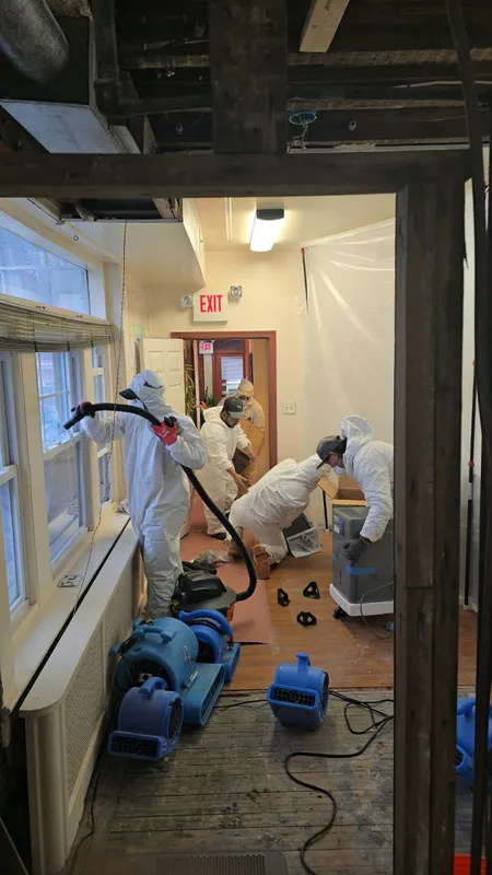 Restoration technicians drying a home hallway with air movers after water damage