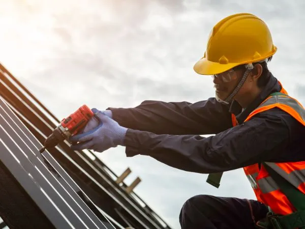 Roofer fastening metal roof panels with a drill