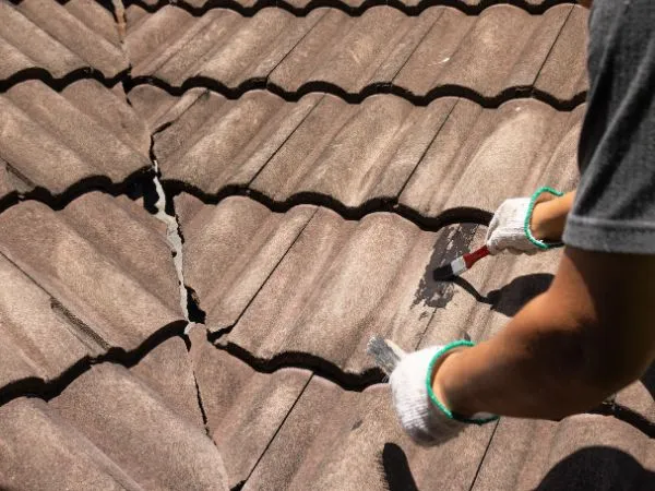 Roofer repairing cracked roof tiles with a trowel
