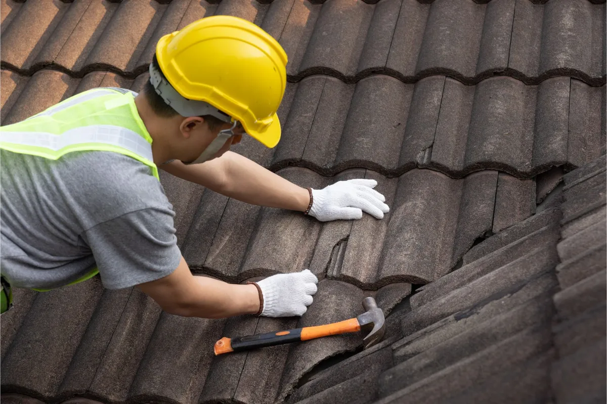 Roofer repairing a cracked tile roof by hand