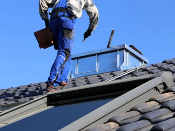 Roofing worker standing on a tiled roof near a skylight