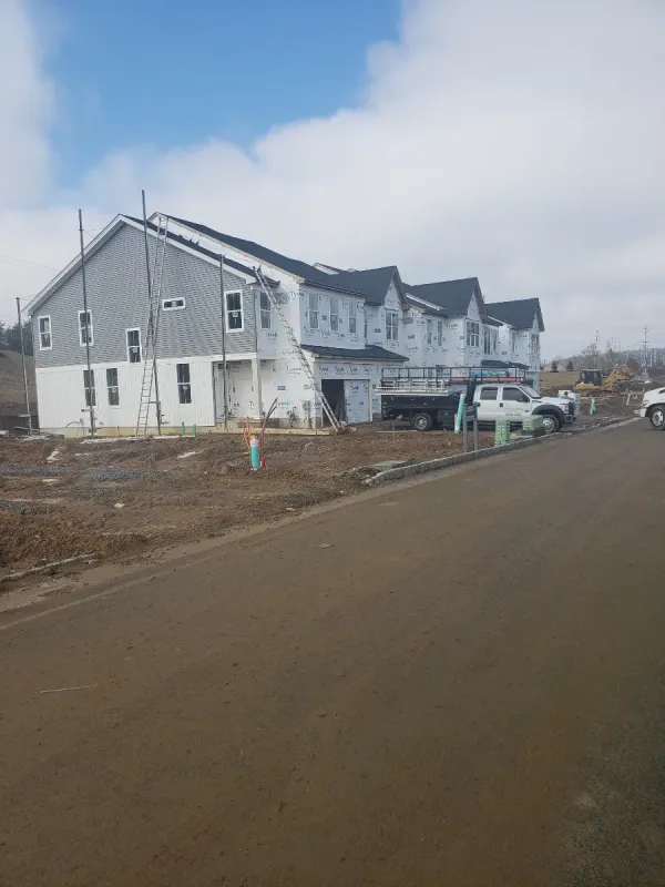 New townhome construction with siding, scaffolding and work trucks on site