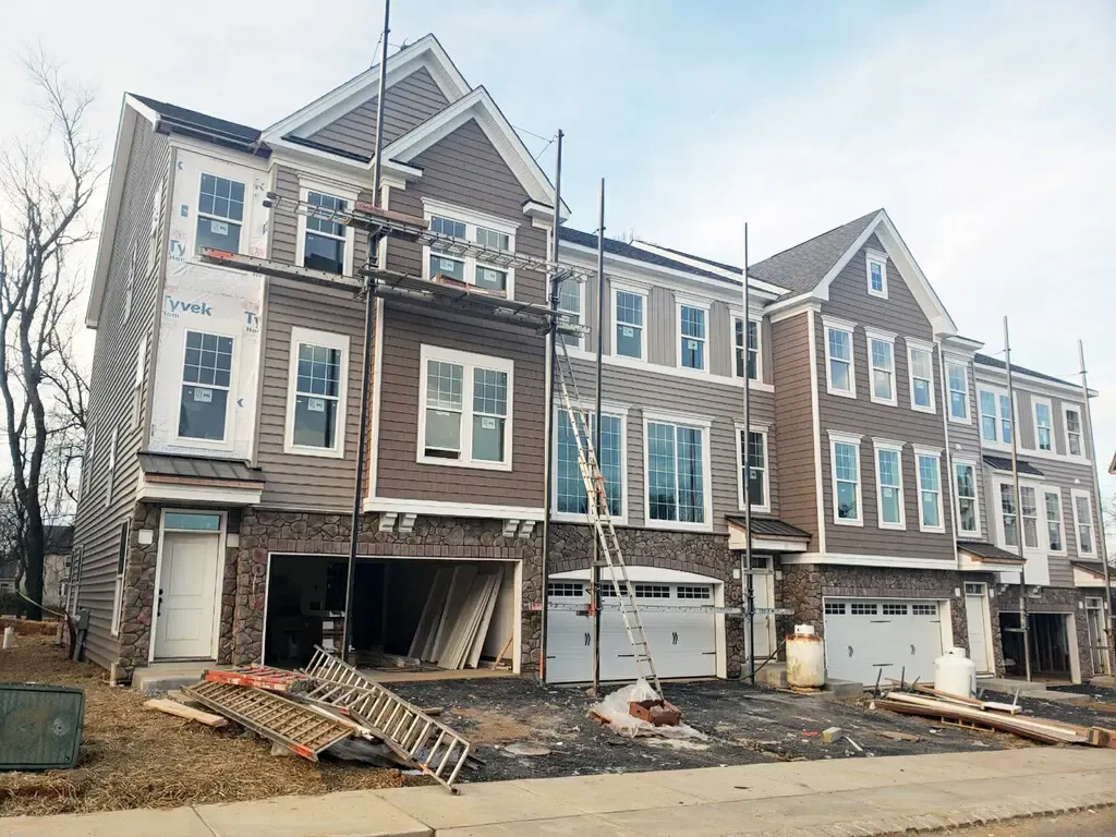 New townhouses under construction with stone veneer garages and scaffolding