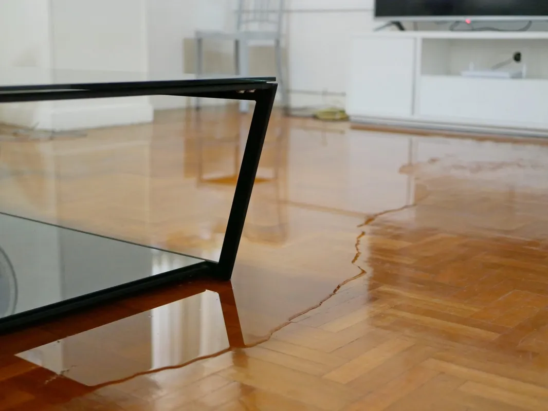 Water-damaged herringbone hardwood floor with warped boards in a home