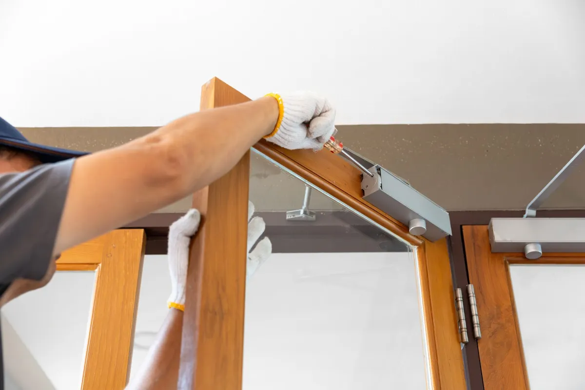 Worker installing a wooden exterior door with new hardware